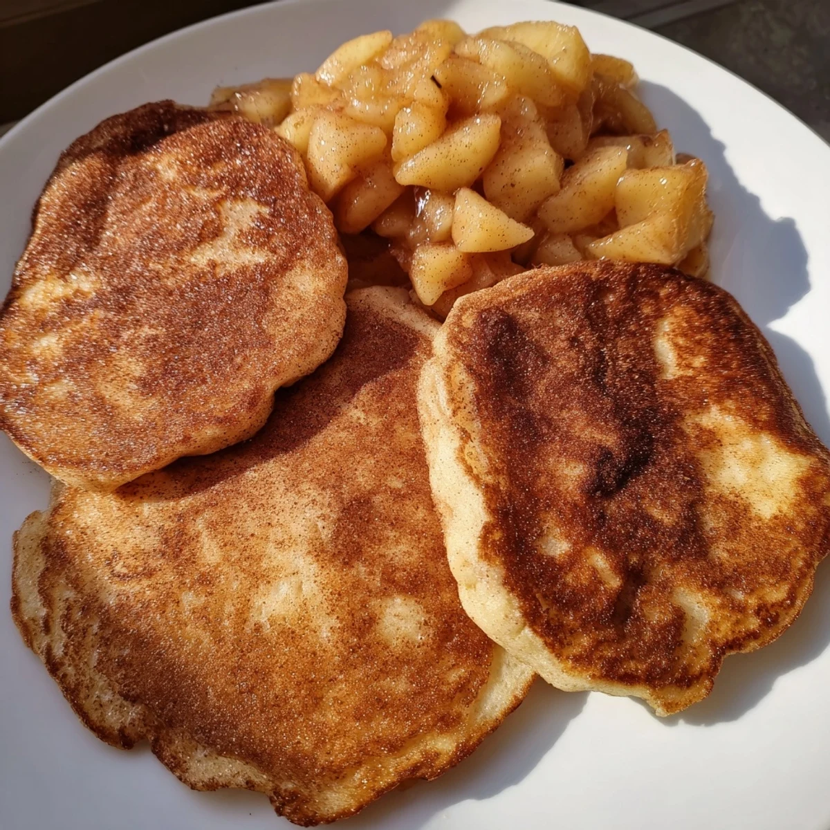 Warm Quarkkeulchen with a dusting of cinnamon sugar, plated beside vibrant, chunky apple compote.