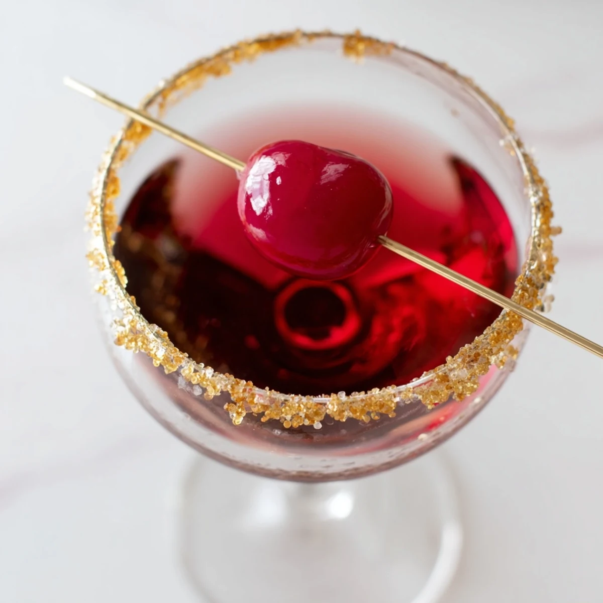 A chilled Rococo Kirsch Martini with a shimmering gold rim and a festive cherry garnish.
