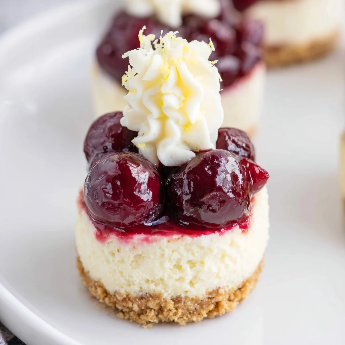 Close-up of elegant Kirsch-Rococo mini cheesecakes, showing the layered creamy texture and almond crust.