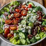 Genussvoller griechischer Salatbowl mit saftigen Tomaten, Gurken und würziger griechischer Vinaigrette.