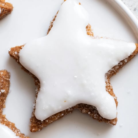 Freshly baked Cinnamon Stars, glistening with white icing, perfect for a festive holiday treat.