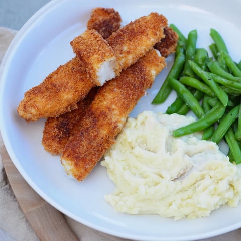 Golden, crispy oven fish sticks with creamy mashed potatoes and vibrant green peas, a delightful meal.