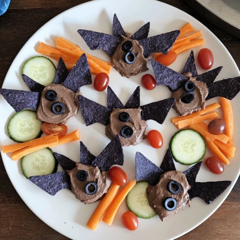 Spooky Bat Bean Dip Platter with black bean bats, vibrant veggies, and tortilla chips for Halloween appetizer.
