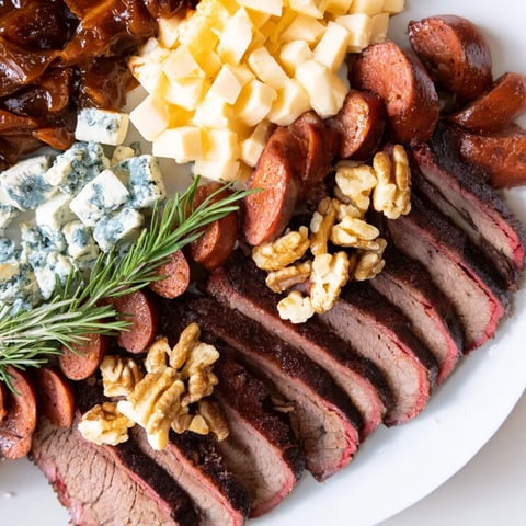A rustic charcuterie board features a vibrant Smoky BBQ & Bourbon Companion appetizer with delicious meats.