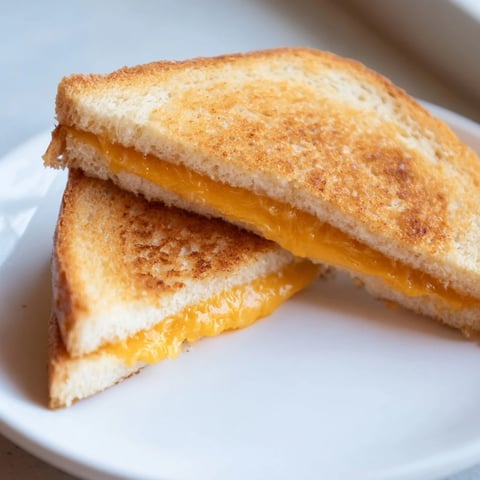 Golden, crispy air fryer grilled cheese sandwich with melted cheese, ready to be sliced and enjoyed.