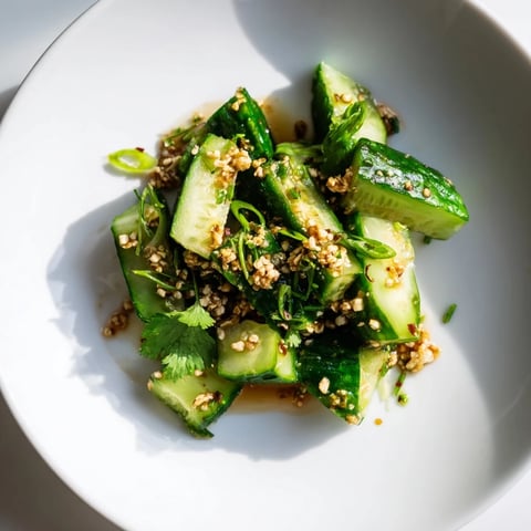 A vibrant Chinese Spicy Smashed Cucumber Salad drizzled with sesame oil, ready to serve and enjoy.