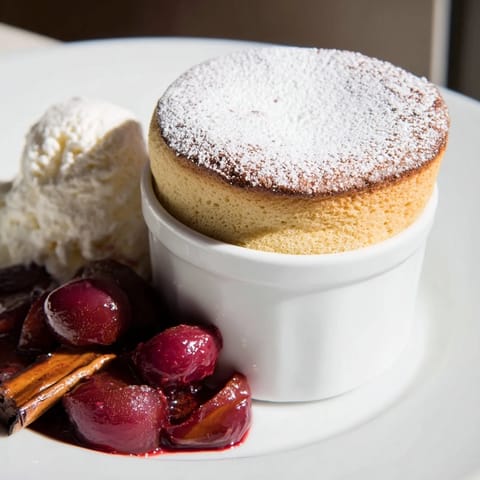 A warm bowl showcases the delicate Mulled Wine Soufflé, crowned with a dusting of icing sugar.