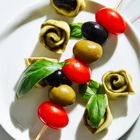 Freshly assembled appetizer skewers with tortellini, pesto, and olives, ready to be enjoyed.