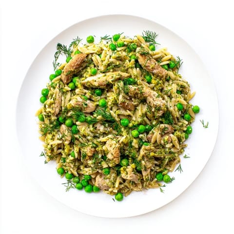 Steam rises from the bubbling Lemon Herb Chicken Orzo Skillet, revealing tender chicken and vibrant green peas mixed with orzo.