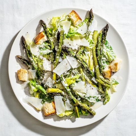 Charred asparagus spears on a bed of crisp romaine with creamy yogurt Caesar dressing and crunchy homemade croutons for a fresh, tangy flavor.