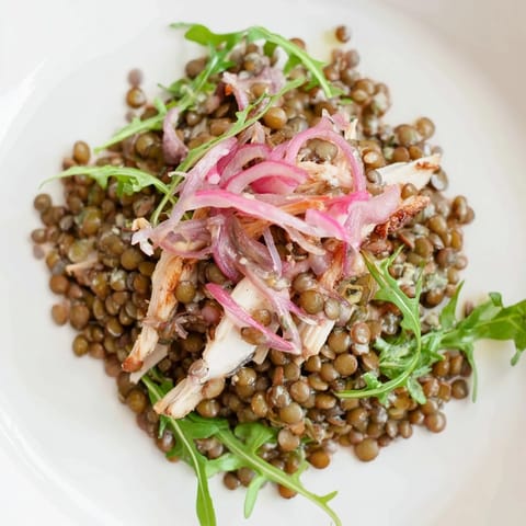 Ein leckerer Lentil & Chicken Spring Salad mit knusprigem Arugula, saftigem Hähnchen und tangigen Pickled-Onions auf einem teller.