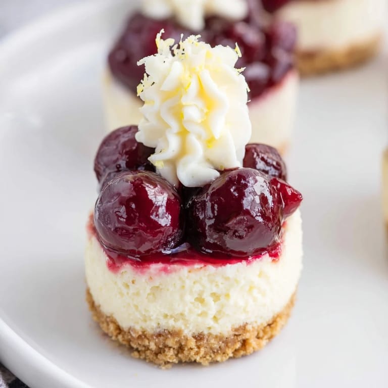 Close-up of elegant Kirsch-Rococo mini cheesecakes, showing the layered creamy texture and almond crust.