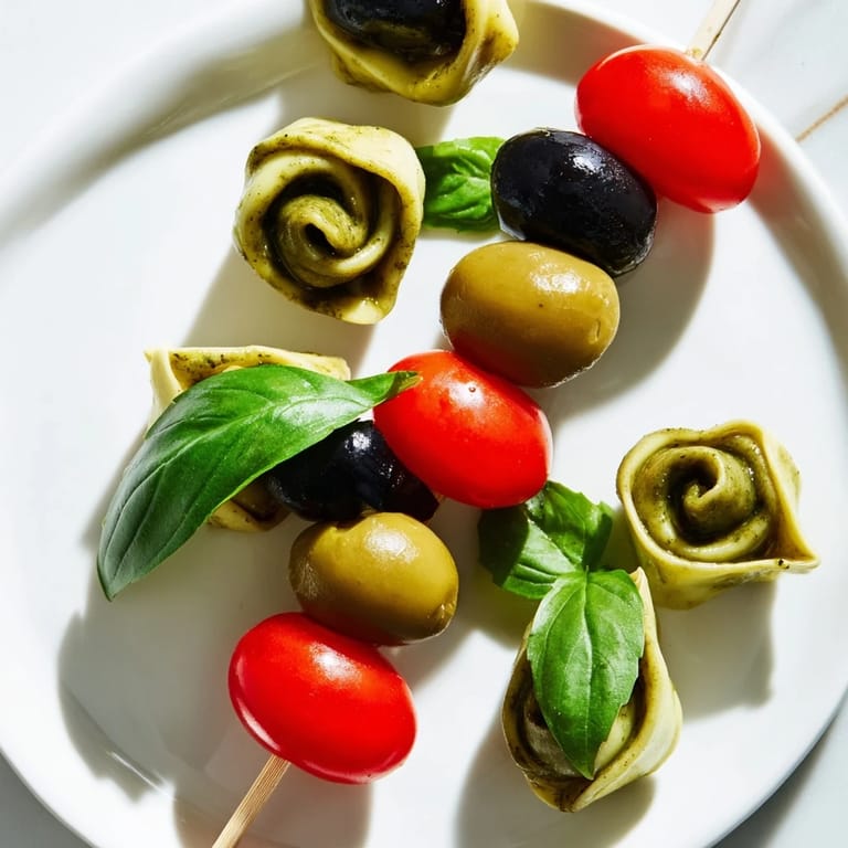 Freshly assembled appetizer skewers with tortellini, pesto, and olives, ready to be enjoyed.